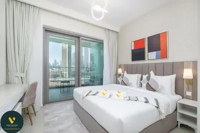 a bedroom with a large white bed and a balcony at Vogue Downtown Views II with Direct Access to Dubai Mall Via a Climate Controlled Bridge, Two Bedroom Apartment with Balcony and Burj Khalifa View in Dubai