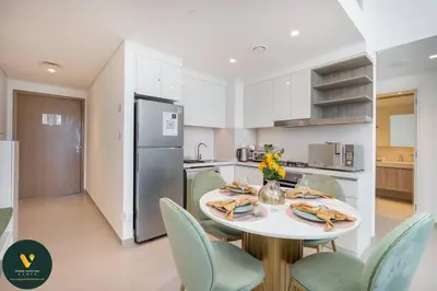 a kitchen with a table with chairs and a refrigerator at Vogue Downtown Views II with Direct Access to Dubai Mall Via a Climate Controlled Bridge, One Bedroom Apartment with Balcony and City View in Dubai