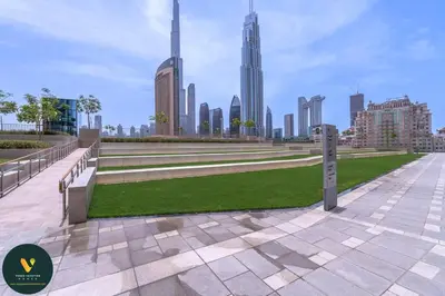a park with benches and grass in front of a city at Vogue Downtown Views II with Direct Access to Dubai Mall Via a Climate Controlled Bridge, One Bedroom Apartment with Balcony and City View in Dubai