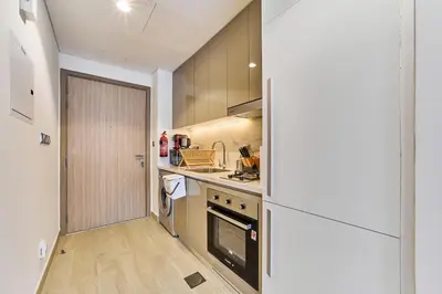a kitchen with a refrigerator and a stove top oven at Chic Studio in Azizi Riviera with Modern Amenities in Dubai