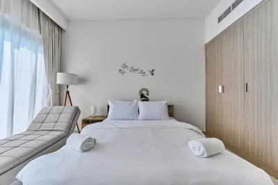 a white bedroom with two beds and a window at Chic Studio in Azizi Riviera with Modern Amenities in Dubai