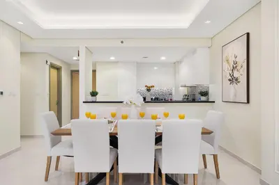 a dining room with a table and white chairs at Paramount Midtown by Luxe Living in Dubai