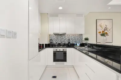 a white kitchen with black and white appliances at Paramount Midtown by Luxe Living in Dubai