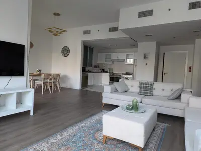a living room with white furniture and a kitchen at Stunning 2BR Apartment with Full Marina View in Dubai