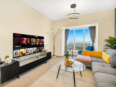 a living room with a couch and a tv at Iconic Palm & Sea Views on 58th Floor Skyline Apt in Dubai