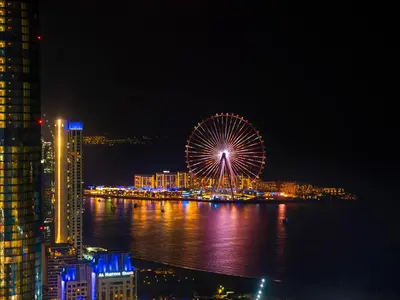 a ferris wheel in a city at night at Iconic Palm & Sea Views on 58th Floor Skyline Apt in Dubai