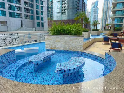 a pool with blue water and benches in a city at Huzz 59 - La Maison Blanche in Dubai