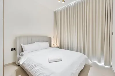 a bedroom with a white bed and a window at Savis Home - Enjoy the City Skyline View 1BR in Binghatti Venus JVC in Dubai