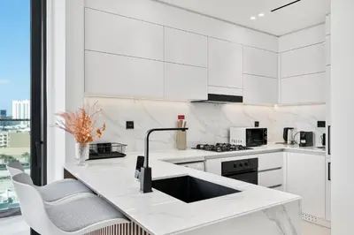 a white kitchen with white cabinets and a counter at Savis Home - Enjoy the City Skyline View 1BR in Binghatti Venus JVC in Dubai