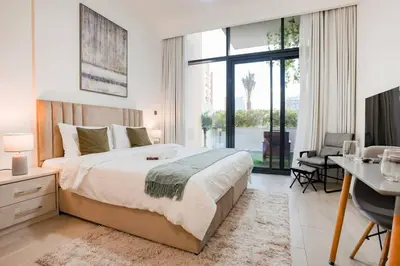 a bedroom with a large bed with a desk and a desk at Cozy Studio with Garden Views in Nad Al Sheba in Dubai