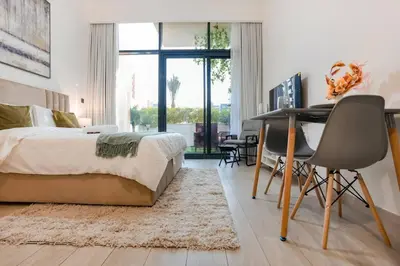 a bedroom with a bed and a desk and a table and chairs at Cozy Studio with Garden Views in Nad Al Sheba in Dubai