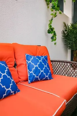 an orange couch with two blue pillows on it at Cozy Studio with Garden Views in Nad Al Sheba in Dubai