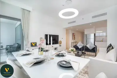 a white dining room with a table and a living room at Vogue Downtown Views II with Direct Access to Dubai Mall Via a Climate Controlled Bridge, Two Bedroom Apartment with Balcony and Burj Khalifa View in Dubai