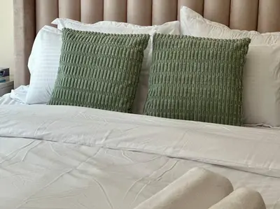 a bed with white sheets and green pillows at Luxury Studio Near Burj Khalifa in Dubai