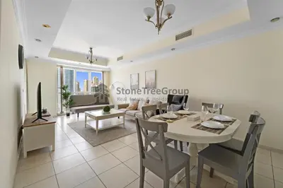 a dining room and living room with a table and chairs at High-floor 2BR at Palladium, JLT - Near Metro in Dubai