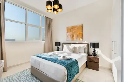 a white bedroom with a large bed and windows at Urban Sanctuary Studio with Pool, Gym and Playground in Dubai