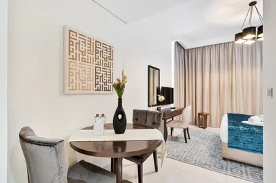 a living room with a table and a bedroom at Urban Sanctuary Studio with Pool, Gym and Playground in Dubai