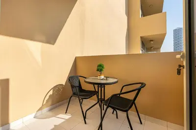 a small table with chairs and a plant on a balcony at Urban Sanctuary Studio with Pool, Gym and Playground in Dubai