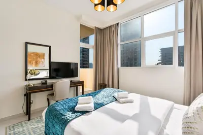 a hotel room with a bed and a desk and window at Urban Sanctuary Studio with Pool, Gym and Playground in Dubai