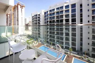 a balcony with white chairs and a view of a building at NewArabian Azizi Riviera Studio in Dubai