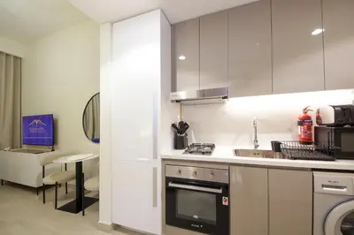 a kitchen with white cabinets and a stove top oven at NewArabian Azizi Riviera Studio in Dubai