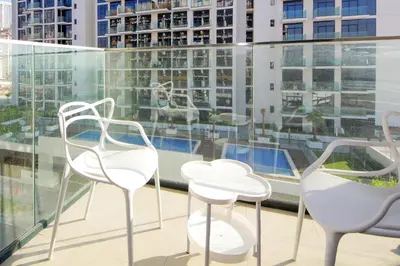 three chairs and a table on a balcony with buildings at NewArabian Azizi Riviera Studio in Dubai