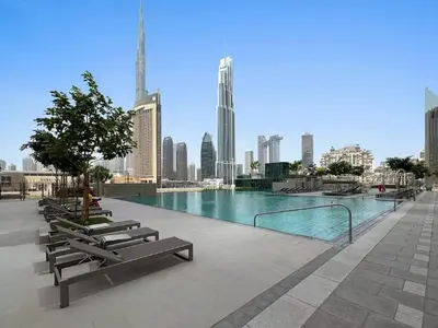 a swimming pool with benches and a city skyline at Vogue Downtown Views II with Direct Access to Dubai Mall Via a Climate Controlled Bridge, Two Bedroom Apartment with Balcony and Burj Khalifa View in Dubai