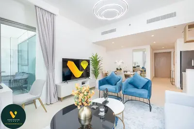 a living room with blue chairs and a tv at Vogue Downtown Views II with Direct Access to Dubai Mall Via a Climate Controlled Bridge, Two Bedroom Apartment with Balcony and Burj Khalifa View in Dubai