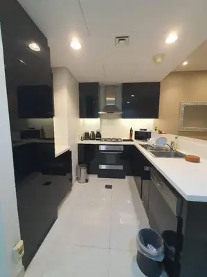 a kitchen with black cabinets and white counter tops at damac maison canal view Luxuary 1BHK in heart downtow in Dubai