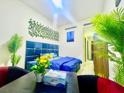 a bedroom with a blue bed and a table with flowers at Brand New Studio Near ADCB Metro in Dubai