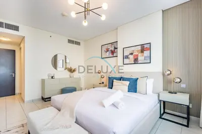 a white bedroom with a large bed and a table at Stylish 2BR in Sky Gardens, DIFC by Deluxe Holiday Homes in Dubai