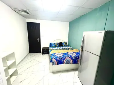 a small room with a bed and a refrigerator at Flat in Dubai Al Karama in Dubai