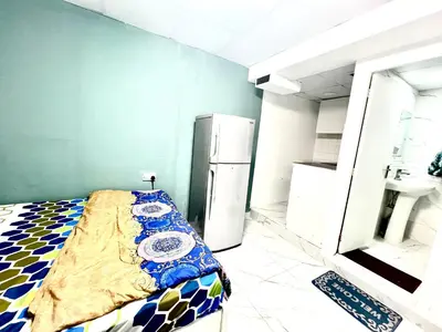 a kitchen with a bed in a room with a refrigerator at Flat in Dubai Al Karama in Dubai