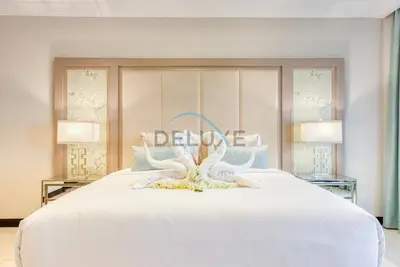 a bedroom with a large white bed with two lamps at Immaculate 4BR Villa with Assistant Room and Private Pool at Frond O Palm Jumeirah by Deluxe Holiday Homes in Dubai