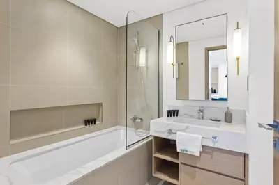 a bathroom with a tub and a sink and a mirror at Luxe Living in 1 Bedroom apartment at 17 Icon Bay in Dubai