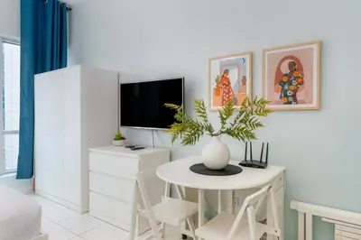 a living room with a table and a tv at White Sage Renovated Studio Nxt to Metro in Dubai
