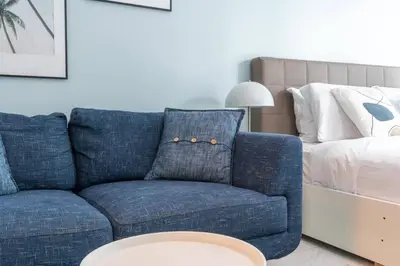 a blue couch in a living room with a bed at White Sage Renovated Studio Nxt to Metro in Dubai