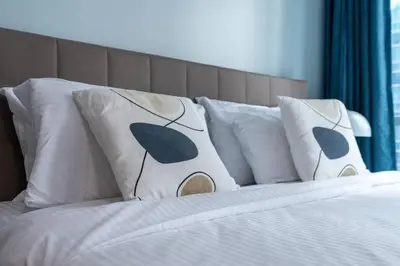a bed with white pillows and a headboard at White Sage Renovated Studio Nxt to Metro in Dubai