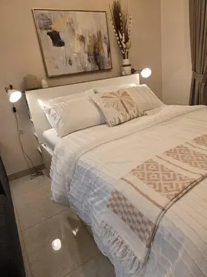 a bedroom with a large bed with two lights on it at Modern Studio Apartment in JVC, behind Circle Mall in Dubai