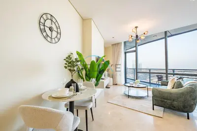 a living room with a table and chairs and a clock at Lively Studio in Sky Gardens, DIFC by Deluxe Holiday Homes in Dubai