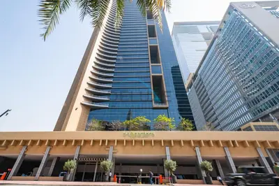 a tall building with a palm tree in front of it at Lively Studio in Sky Gardens, DIFC by Deluxe Holiday Homes in Dubai