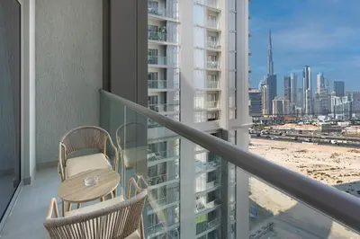 a balcony with a table and chairs and a view of a city at Modern 1br Oasis in Sobha Creek Vista A, MBR City - Allsopp & Allsopp in Dubai