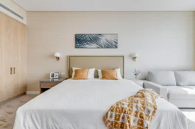 a bedroom with a large white bed and a couch at Luxury Palm Tower Studio Apartments with Pool and Fantastic Sea View in Dubai