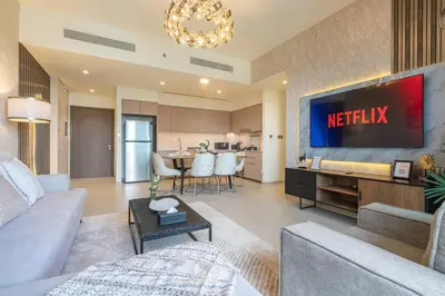 a living room with a television and a kitchen at Lux 2 King Bed Suite - Grande Signature Residences in Dubai