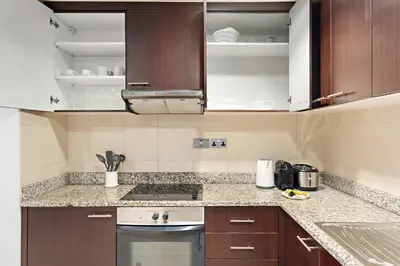 a kitchen with wooden cabinets and a stove top oven at Silkhaus Gallery Studio at Sky Gardens in Heart of DIFC in Dubai