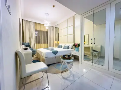 a bedroom with a bed and a table and a chair at 1BHK in Damac Masion mall street in Dubai