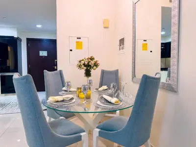 a dining room with a glass table and blue chairs at 1BHK in Damac Masion mall street in Dubai