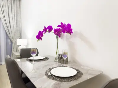 a table with a vase of purple flowers and wine glasses at Furnished Studio Azizi Riviera 3 in Dubai