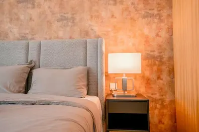 a bedroom with a bed with a lamp on a table at NEW Cozy & Stylish APT with Pool & Gym Access in Dubai