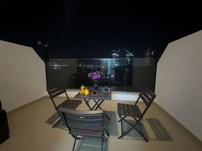 a table and chairs on a balcony at night at Studio in Azizi Riviera Dubai in Dubai